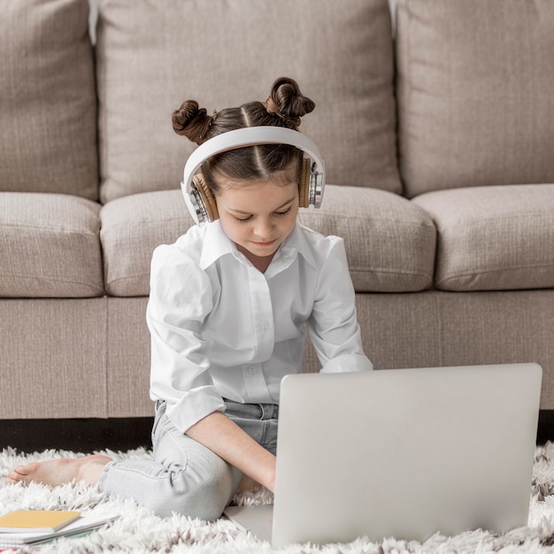 Niña escuchando a su maestra a través de auriculares en el piso