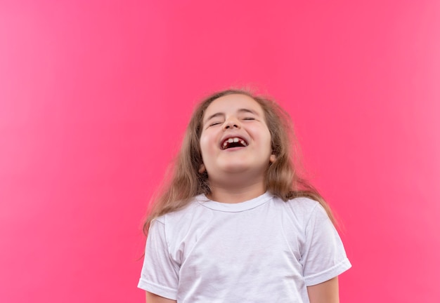 Foto gratuita niña de la escuela alegre con camiseta blanca en la pared rosa aislada