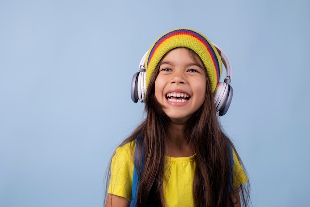 Niña de la escuela asiática escuchando música en auriculares