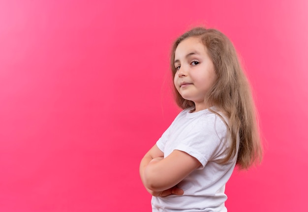 Foto gratuita niña de la escuela con camiseta blanca cruzando las manos en la pared rosa aislada