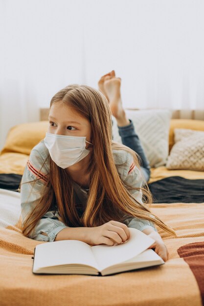 Niña de la escuela estudiando en casa con máscara, aprendizaje a distancia