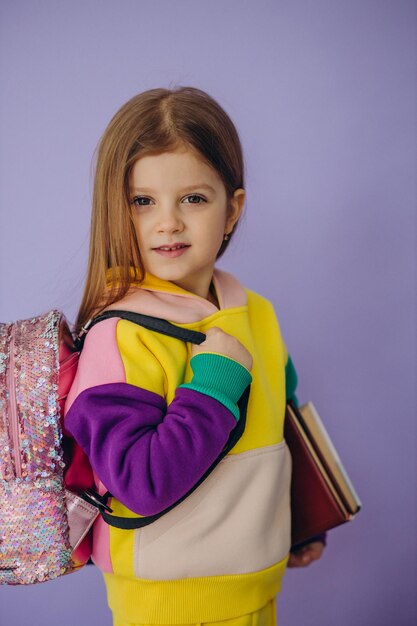 Niña de la escuela con libros y bolsa aislado en estudio