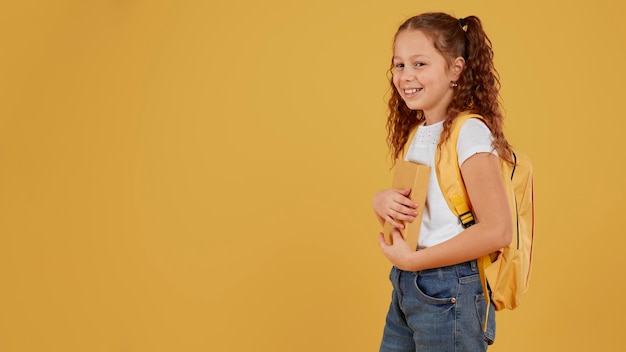 Niña de la escuela de pie lateralmente copia espacio