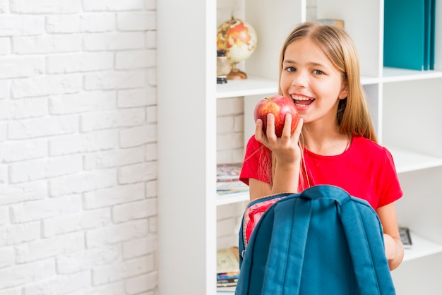 Niña de la escuela primaria con la intención de morder la manzana