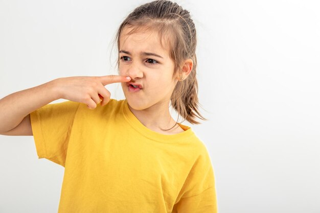 Foto gratuita niña de la escuela se siente mal y no le gusta el olor aislado sobre fondo blanco.