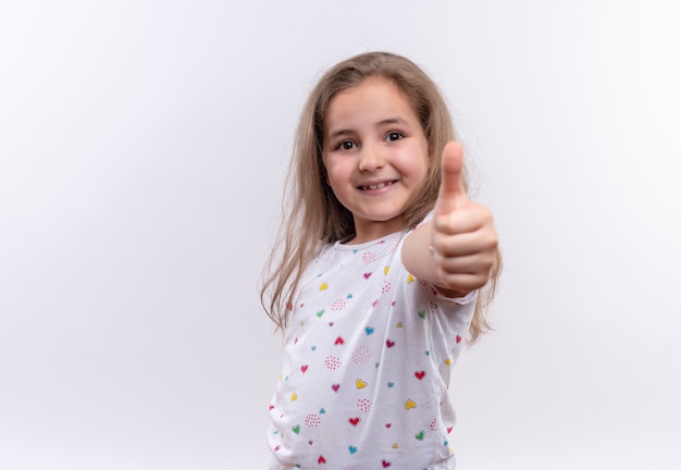 Foto gratuita niña de la escuela sonriente vistiendo camiseta blanca su tumb up sobre fondo blanco aislado