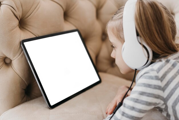 Niña de la escuela usando audífonos y asistiendo a clases en línea