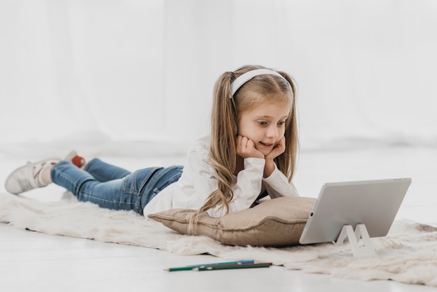 Niña de la escuela usando audífonos y asistiendo a clases en línea