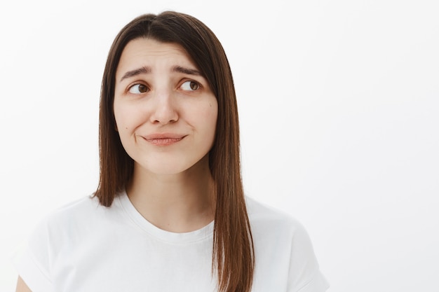 La niña esperaba algo diferente, disgustada y poco impresionada, sonriendo decepcionada, frunciendo el ceño y haciendo muecas de insatisfacción y aversión, mirando hacia la esquina superior derecha