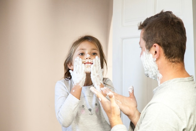 Niña con espuma de afeitar en la cara