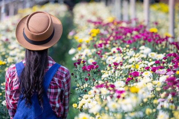 La niña está admirando las flores en el jardín.