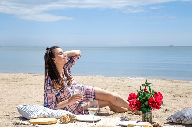 Una niña está descansando en la playa. Un picnic romántico en la orilla arenosa de la playa. El concepto de vacaciones de verano.