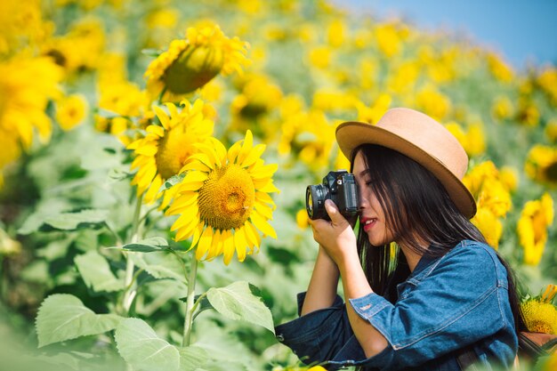 La niña está feliz de tomar fotos en el campo de girasol.