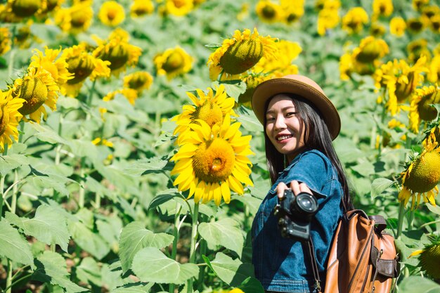 La niña está feliz de tomar fotos en el campo de girasol.