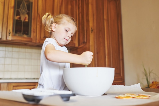 Una niña está preparando una masa para magdalenas.