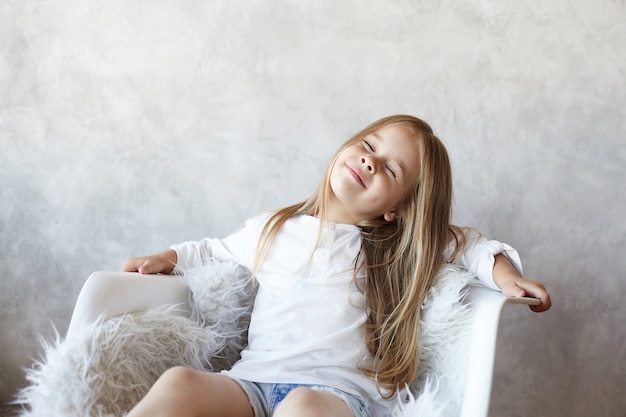 La niña está sentada en la sala