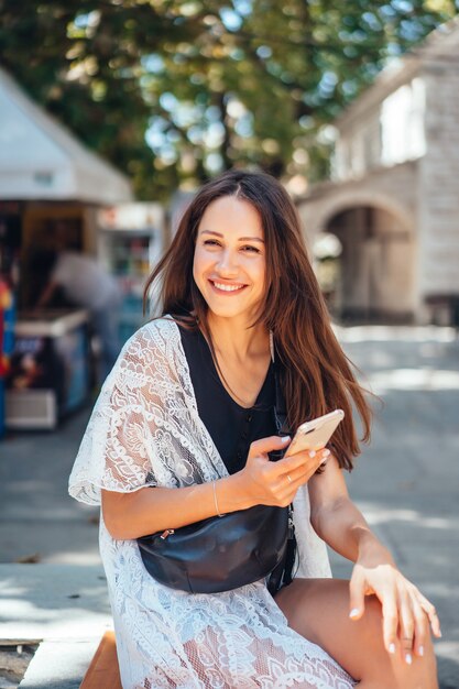 Una niña está sosteniendo un teléfono y posando en la cámara. La Internet. Mensaje.