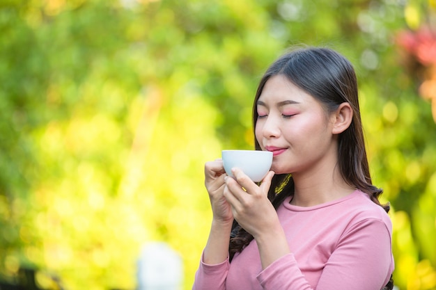 La niña está tomando café con placer en la cafetería.