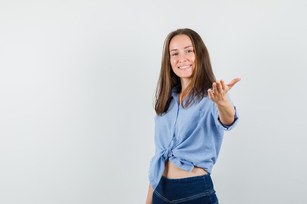 Niña estirando la mano a la cámara en camisa azul