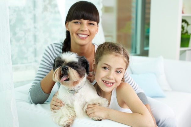 Niña feliz abrazando al perro con su madre