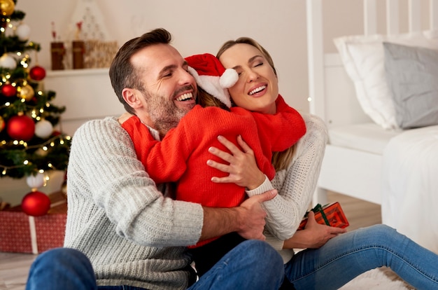 Niña feliz abrazando a sus padres