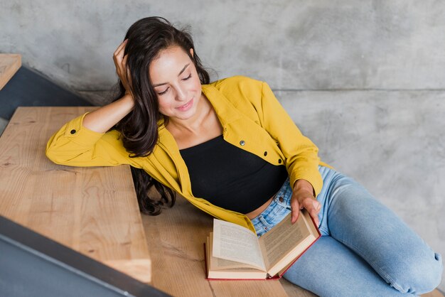 Niña feliz de alto ángulo con el libro en las escaleras