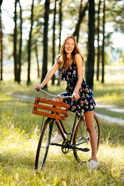 Niña feliz en una bicicleta en el bosque.