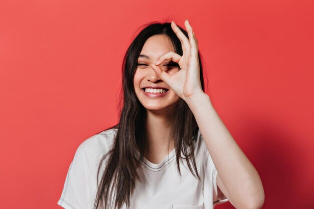 Niña feliz con cabello largo sonríe y muestra el signo ok