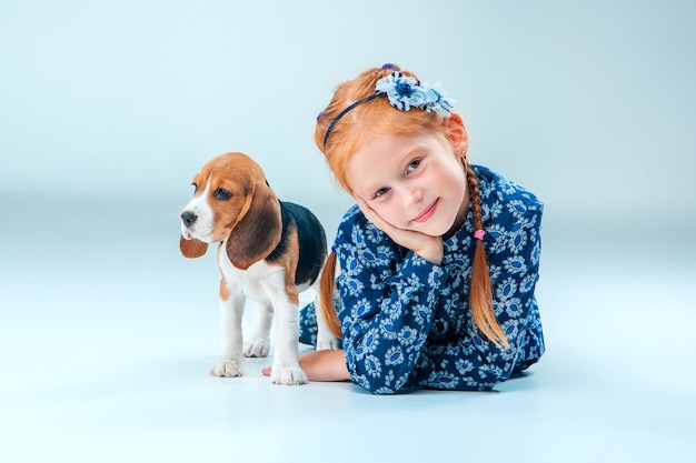 Foto gratuita la niña feliz y un cachorro beagle en pared gris