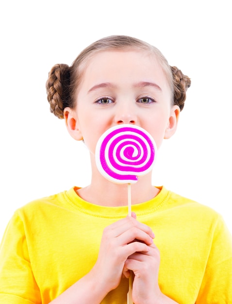 Niña feliz en camiseta amarilla comiendo dulces de colores - aislados en blanco.