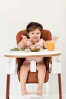 Foto gratuita niña feliz comiendo en silla infantil