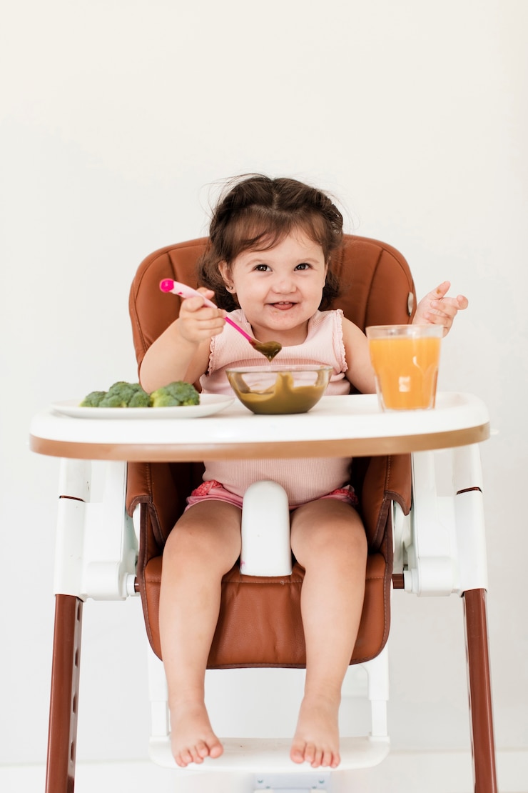 Foto gratuito niña feliz comiendo en silla infantil