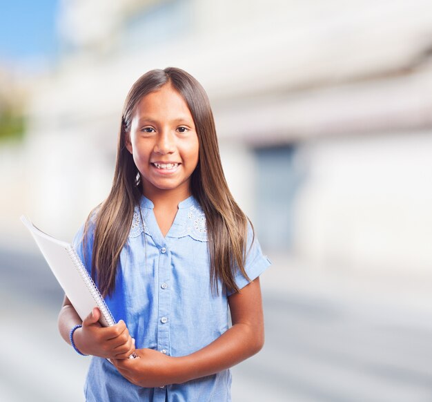 Niña feliz con cuaderno con el fondo borroso