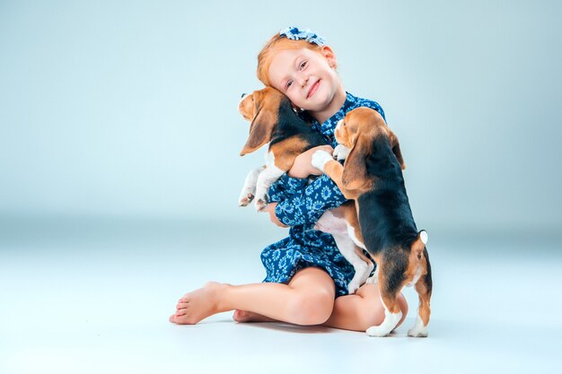 niña feliz y dos cachorros beagle en gris