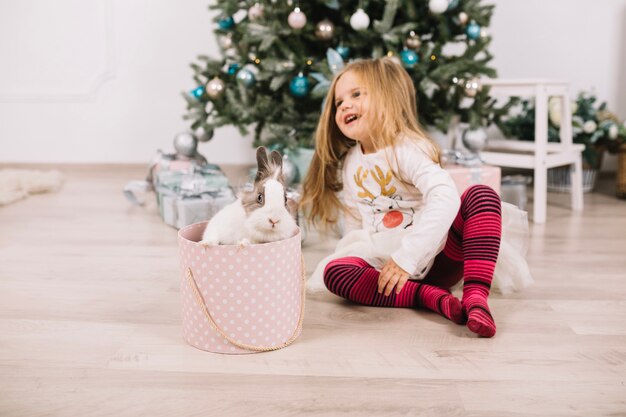 Niña feliz enfrente de árbol de navidad en casa