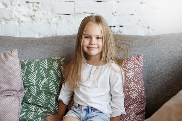 Niña feliz está sentada en la sala de estar