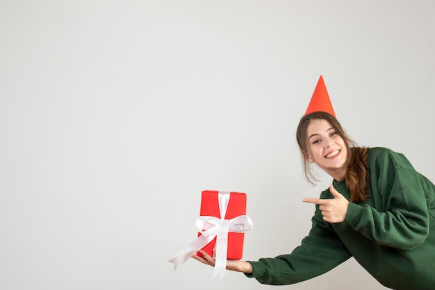 niña feliz con gorro de fiesta apuntando al regalo en blanco