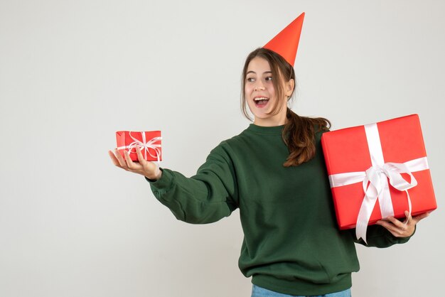 niña feliz con gorro de fiesta dando regalos de navidad en blanco