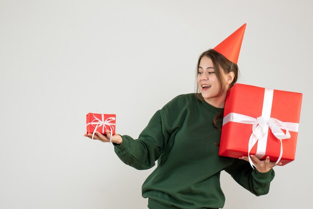 Niña feliz con gorro de fiesta mirando sus regalos de Navidad en blanco