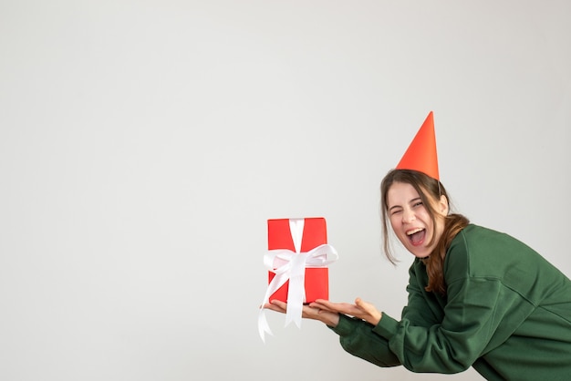 Foto gratuita niña feliz con gorro de fiesta sosteniendo su regalo en blanco