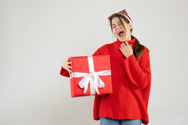 niña feliz con gorro de Papá Noel con regalo en blanco