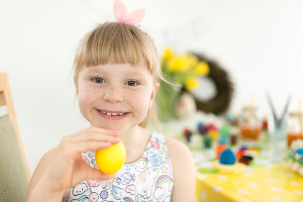 Niña feliz con el huevo de Pascua amarillo