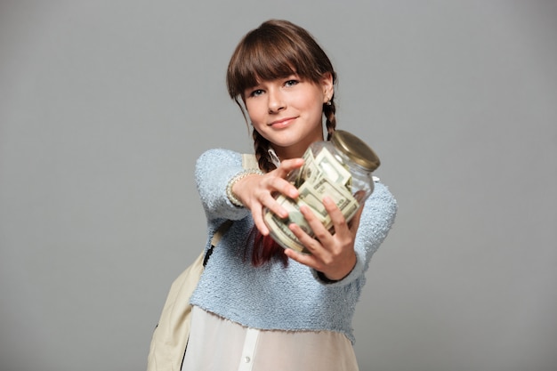 Niña feliz con jarra llena de dinero