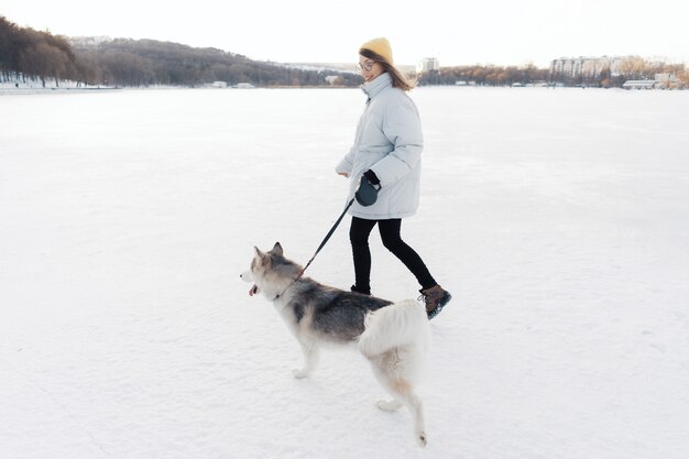 Niña feliz jugando con perro husky siberiano en el parque de invierno