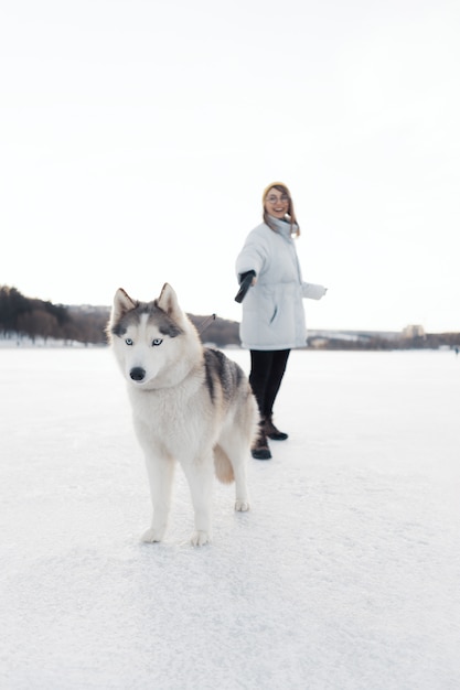 Niña feliz jugando con perro husky siberiano en el parque de invierno