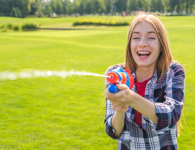 Niña feliz jugando con pistola de agua