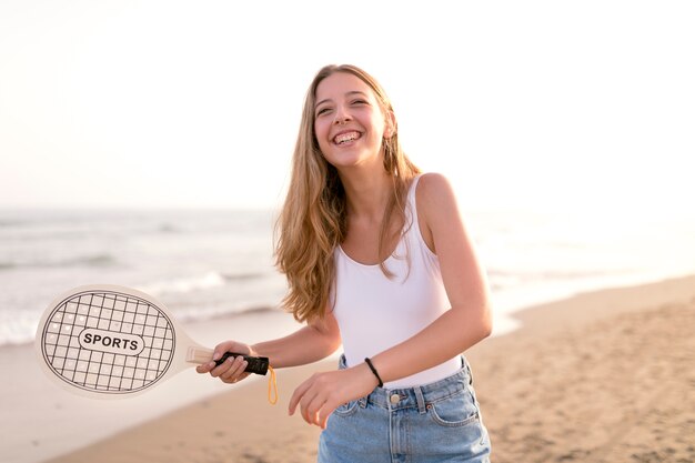 Niña feliz jugando tenis en la playa