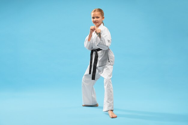 Niña feliz en kimono blanco mirando a la cámara mientras entrenaba