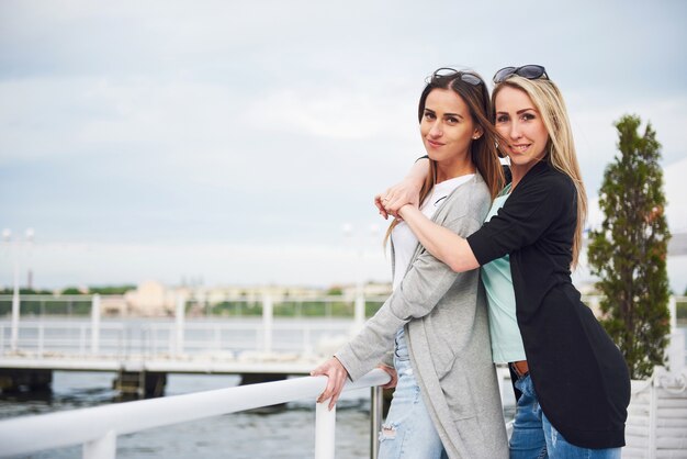 Niña feliz en marcas de ropa con estilo en el muelle cerca del agua.