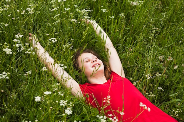 Foto gratuita niña feliz con los ojos cerrados, tumbado en la hierba en la hermosa naturaleza